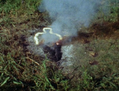 An image of a performance of a silhouette of a human figure that is emitting smoke. 